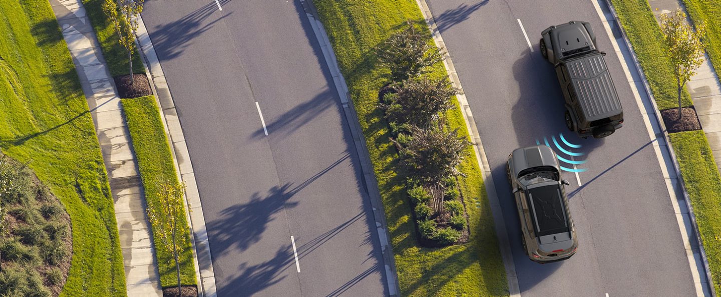 Illustration of sensors monitoring the left rear area of the 2021 Jeep Wrangler, detecting a vehicle in the next lane approaching it from behind.