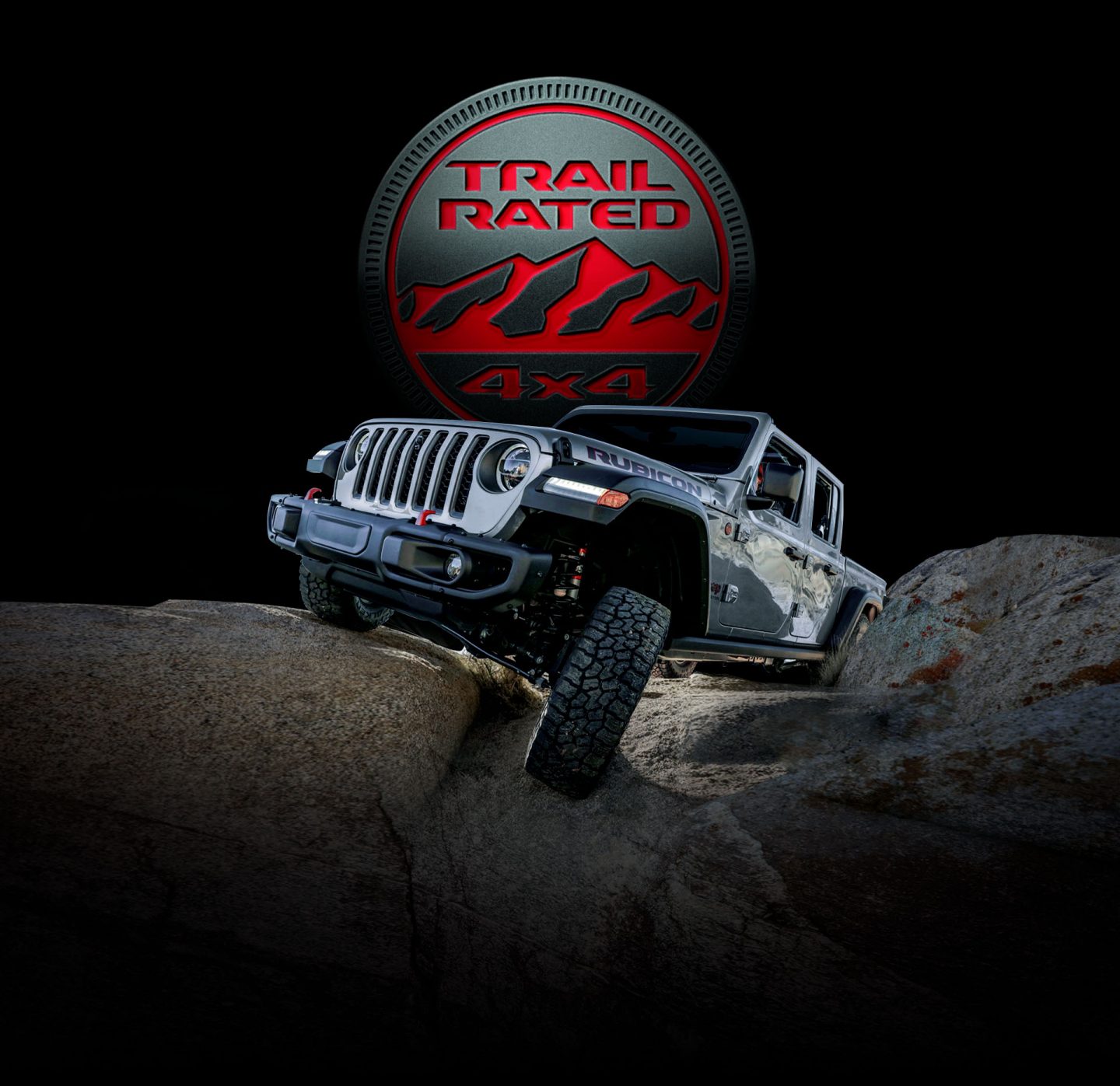 Trail Rated 4x4. The 2022 Jeep Gladiator Rubicon being driven on rocky terrain with one wheel elevated as it climbs a boulder.